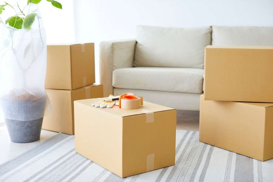 Plusieurs cartons fermés au milieu d'un salon lumineux pour préparer un déménagement en Guadeloupe.