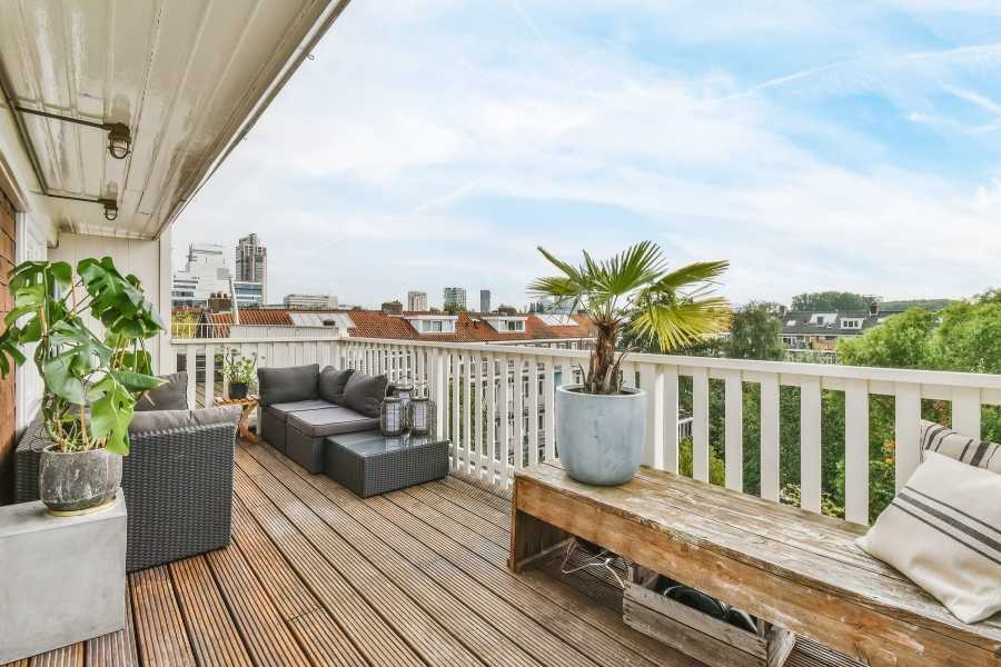 Un balcon aménagé avec un banc rustique fabriqué à partir de palettes en bois et des plantes vertes.