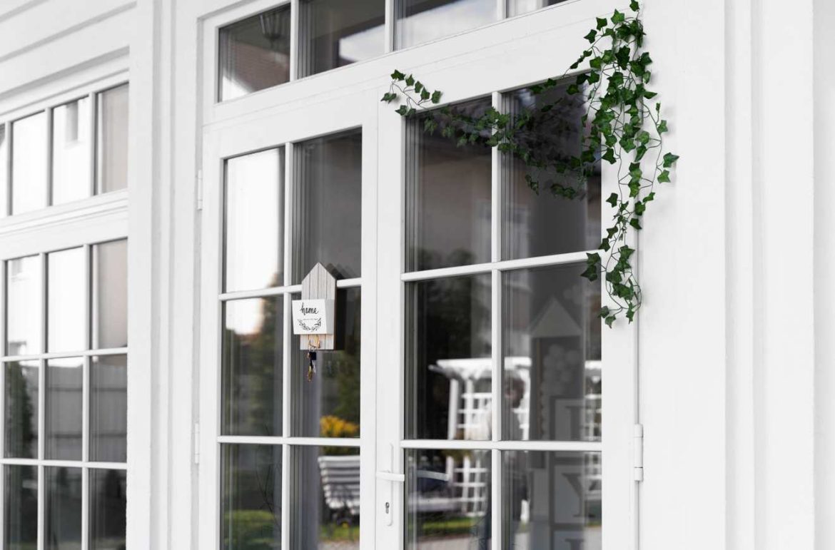 Grande porte-fenêtre blanche avec une décoration florale, illustrant le prix moyen installation menuiserie pvc maison.