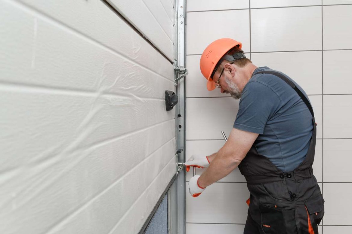 Un technicien en casque de chantier procède à la réparation d'un système de fermeture lors d'un deblocage rideau metallique magasin serrurier paris.